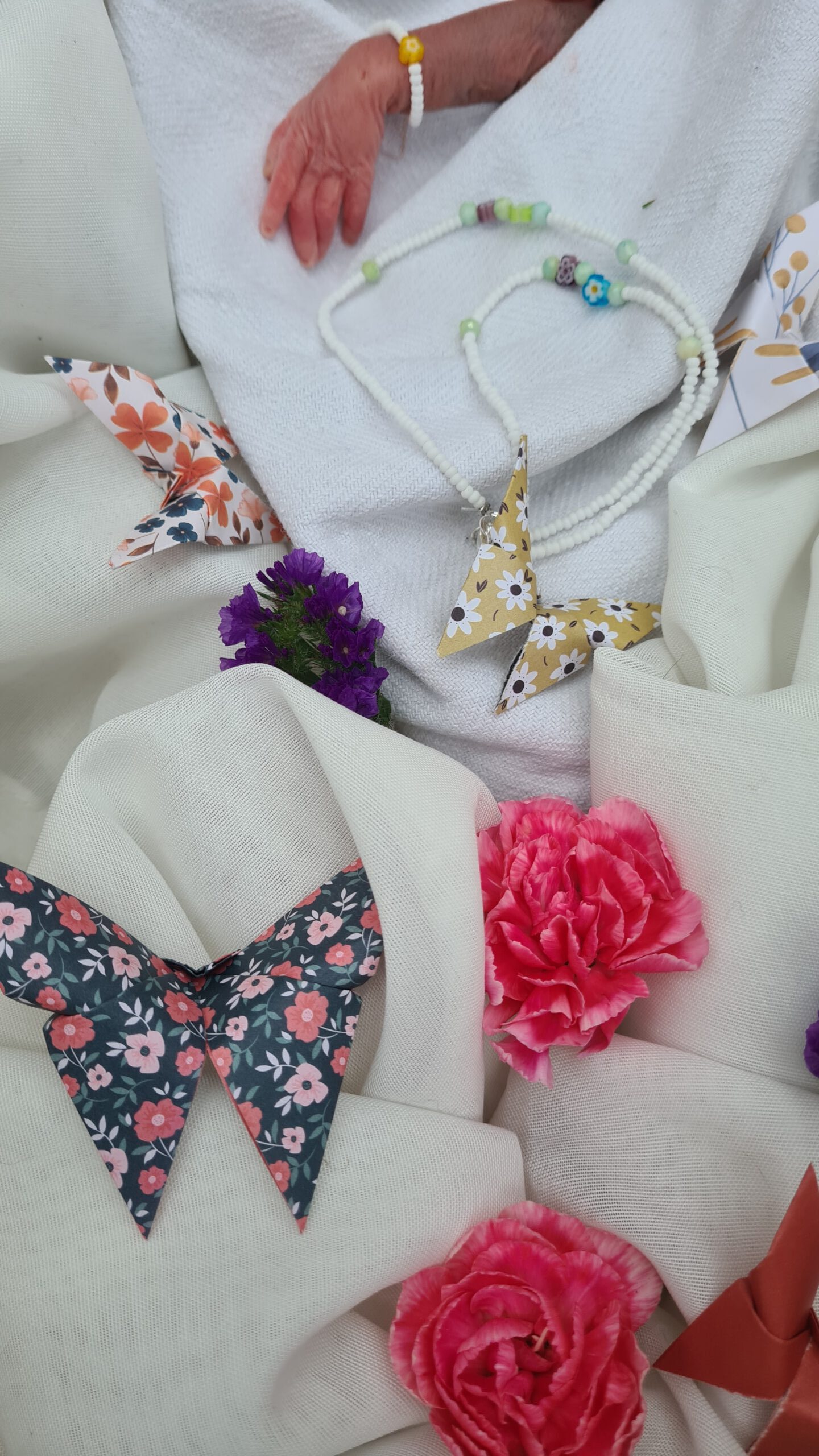 Kinderbestattung in Berlin. Die Hand Sternenkind mit einem Perlenarmband eingebettet in einer weiße Kuscheldecke