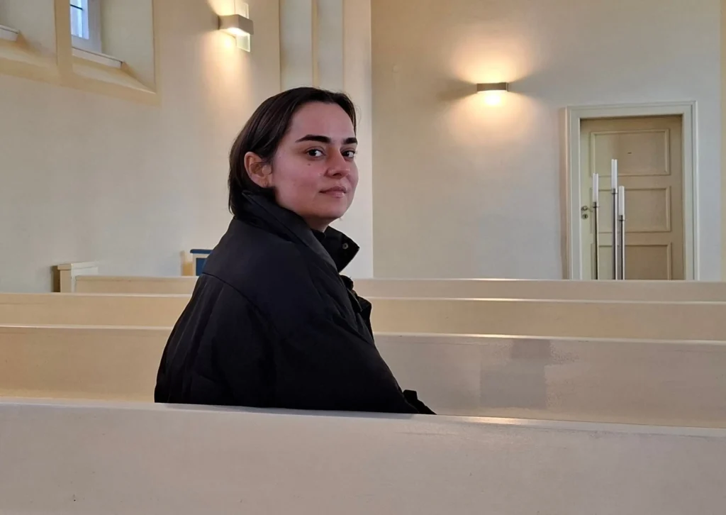 Katja sitzt in der Kapelle während einer Trauerfeier