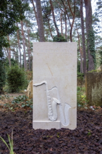 Schöner weißer Grabstein mit einem Relief in Form einer Trompete von Magnolia Bestttaungen