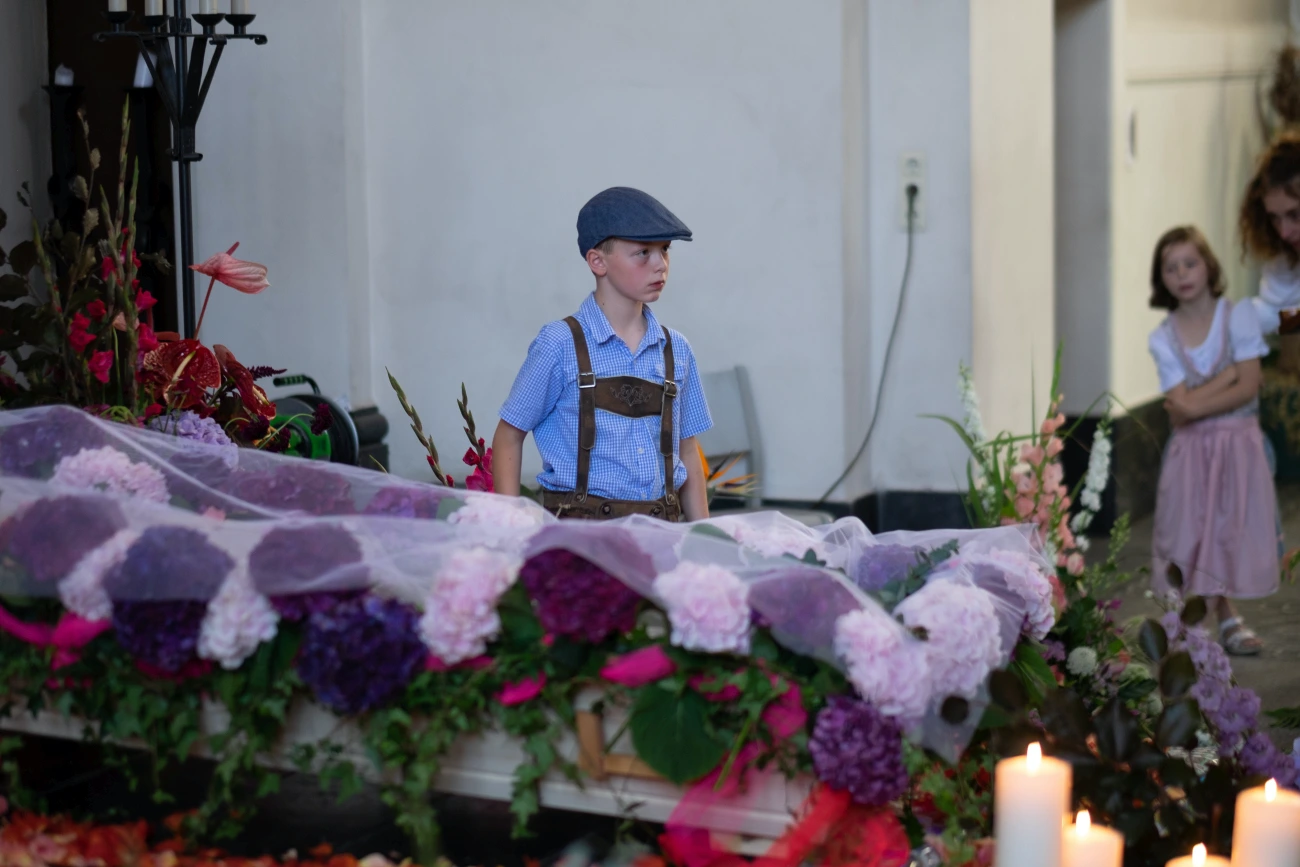 Kind in bayerischer Tracht vor Sarg mit Hortensien-Dekoration – Kinder und Bestattung Berlin mit persönlichen kulturellen Elementen