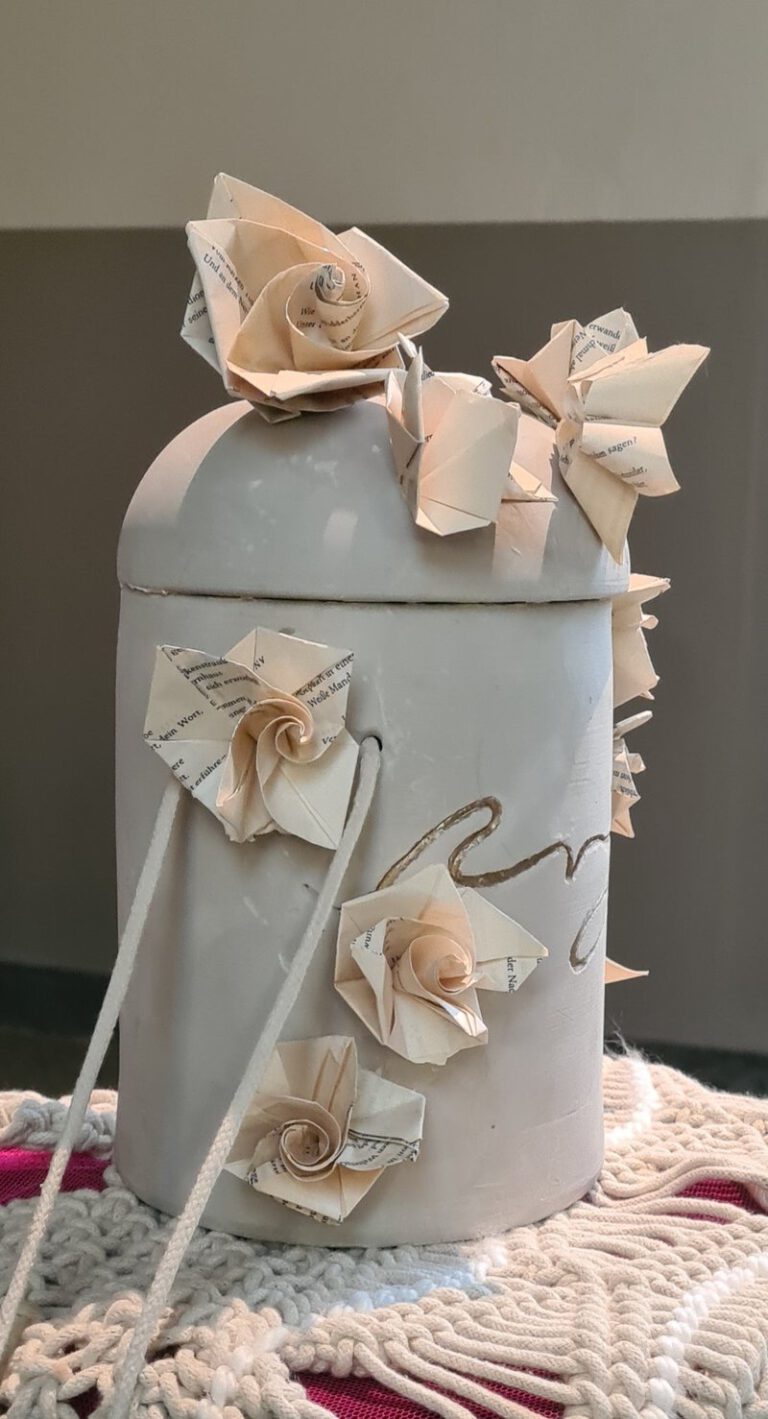 Eine Urne aus Ton auf der Papier Blumen daran geklebt sind