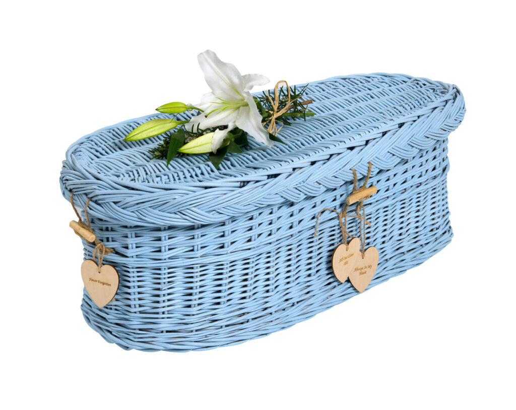 Ein Kindersarg aus geflochtene Weide.Hell Blau angemalt und mit einer weisse Lilie dekoriert vermittelt Vertrauen und unGeborgenheit für die Kinderbestattung bei Atelier Magnolia