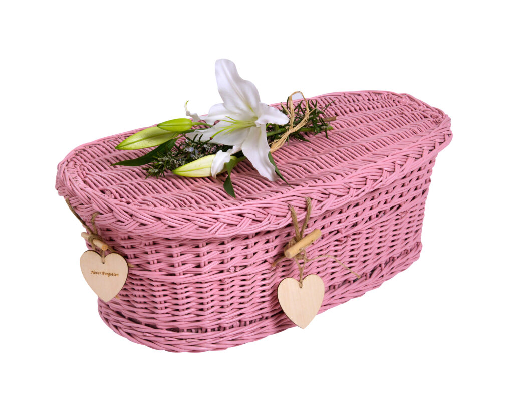 Ein Kindersarg aus geflochtene Weide. Rosa angemalt und mit einer weisse Lilie dekoriert vermittelt Vertrauen und unGeborgenheit für die Kinderbestattung bei Atelier Magnolia