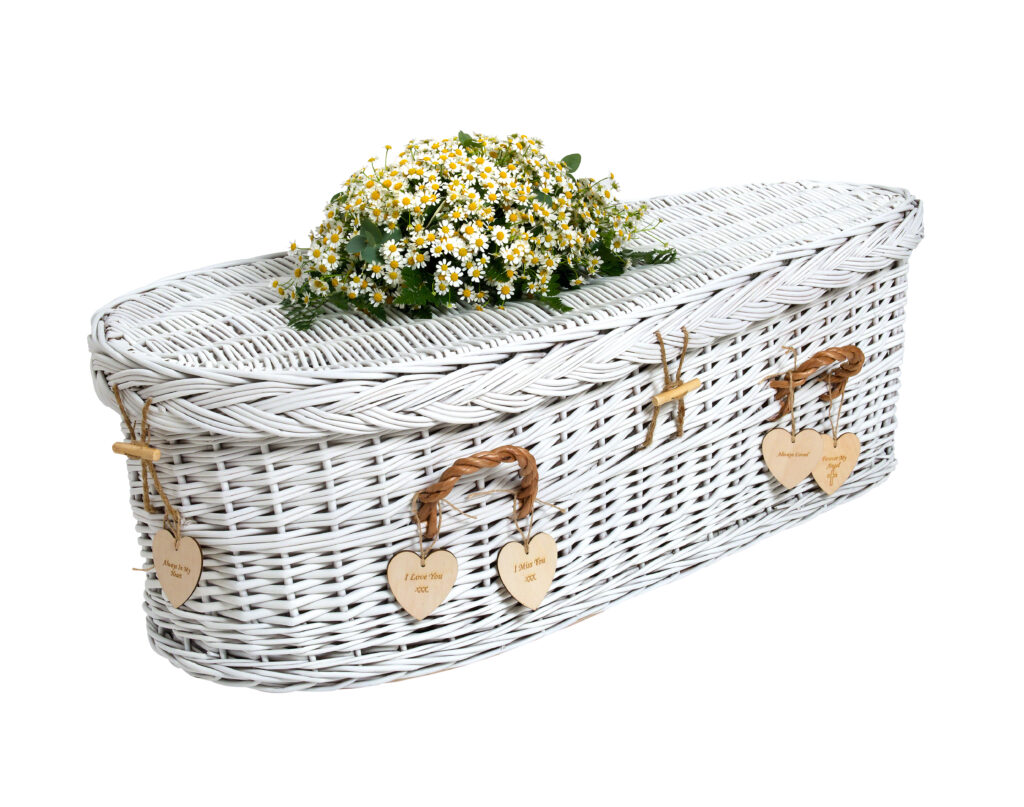 Ein Kindersarg aus geflochtene Weide. Weiss angemalt und mit einem Wiesenblumen Schmuck dekoriert vermittelt Vertrauen und unGeborgenheit für die Kinderbestattung bei Atelier Magnolia