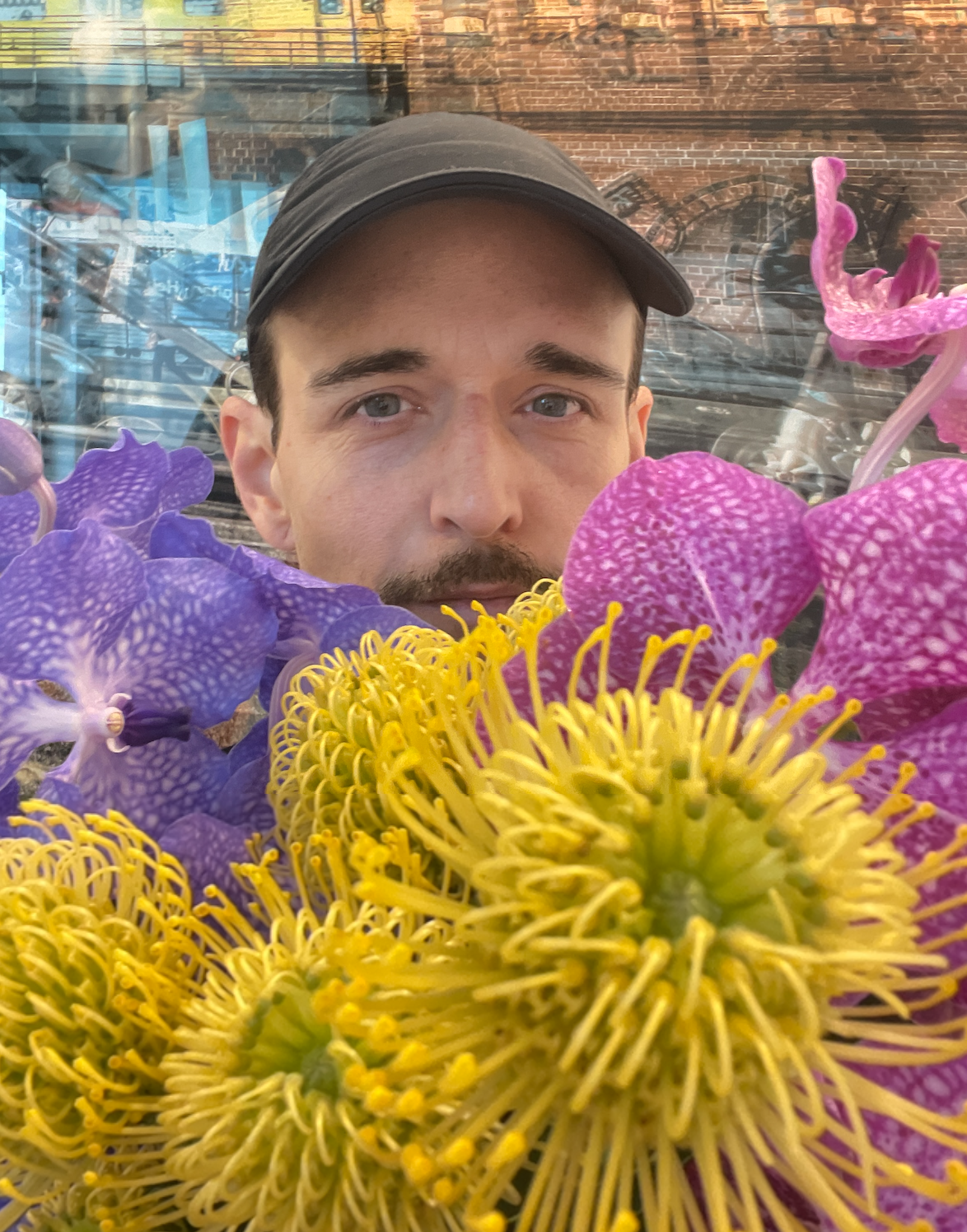 Trauerflorist vom Bestatter Team Ateleir Magnolia schaut durch einen Strauß bunte Blumen